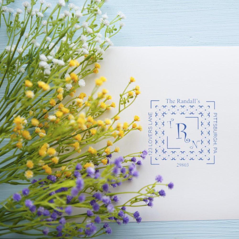 Custom rubber address stamp with monogram and floral border on envelope, ideal for personalized wedding stationery and mailings.