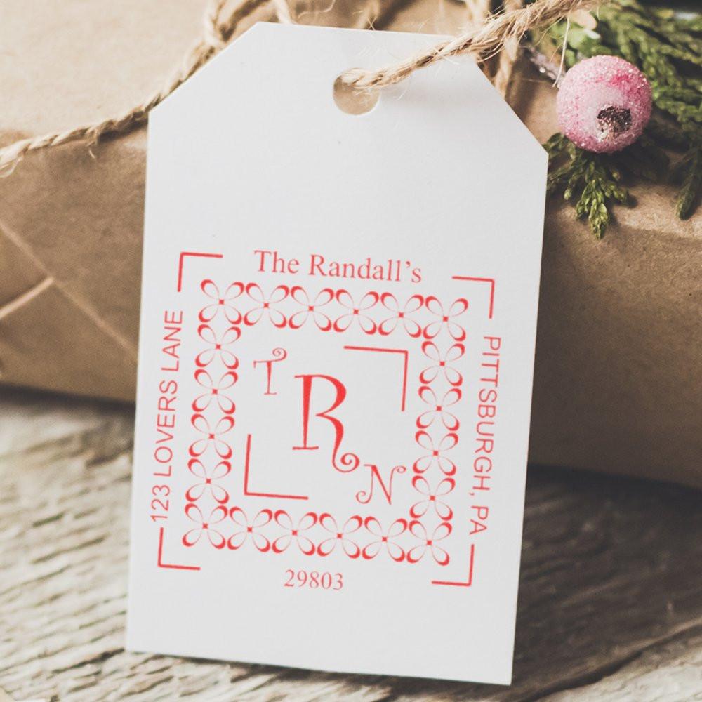 Custom return address rubber stamp on gift tag with monogram, family name, and address for personalized packaging.