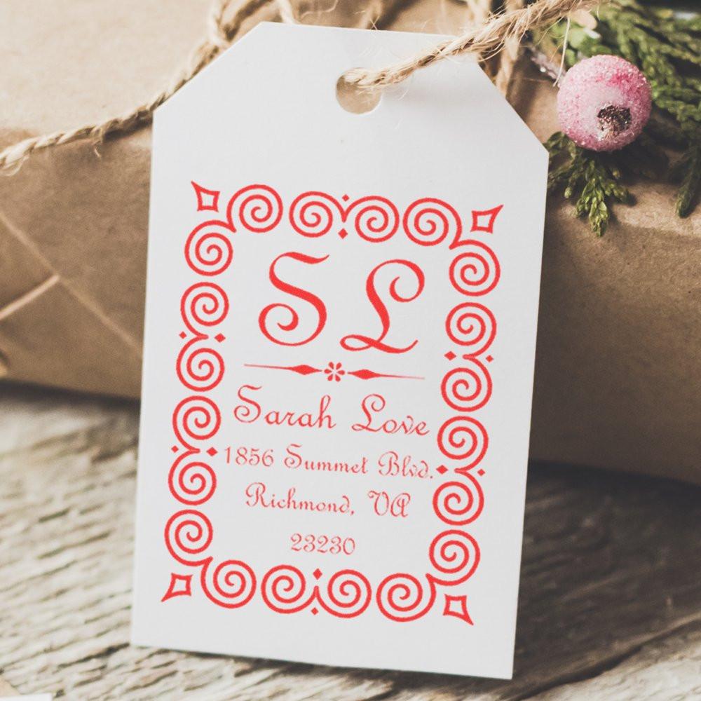 Custom monogram return address rubber stamp on gift tag with ornate red border and personalized name.