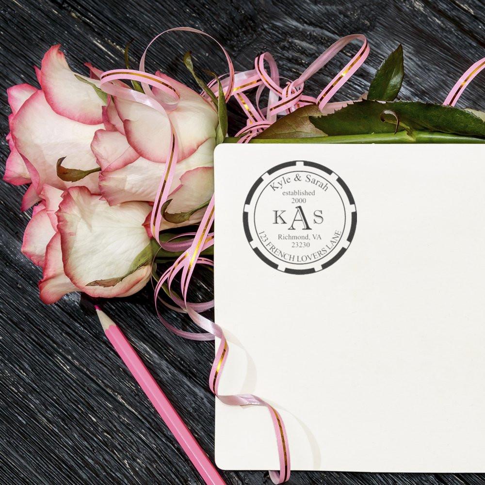 Custom monogram rubber stamp on wedding stationery with pink roses and ribbon for personalized invitations.
