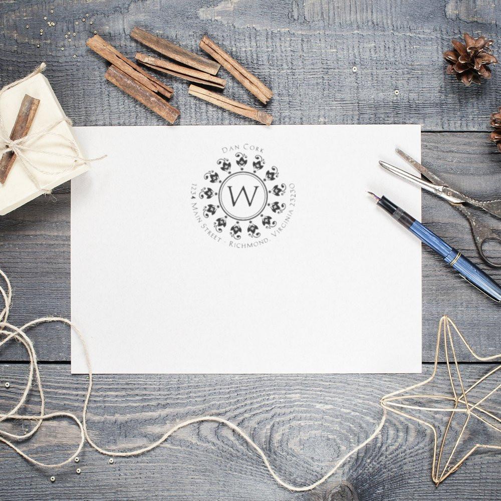 Custom rubber stamp monogram on wedding invitation paper, with address for personalized stationery and event branding.