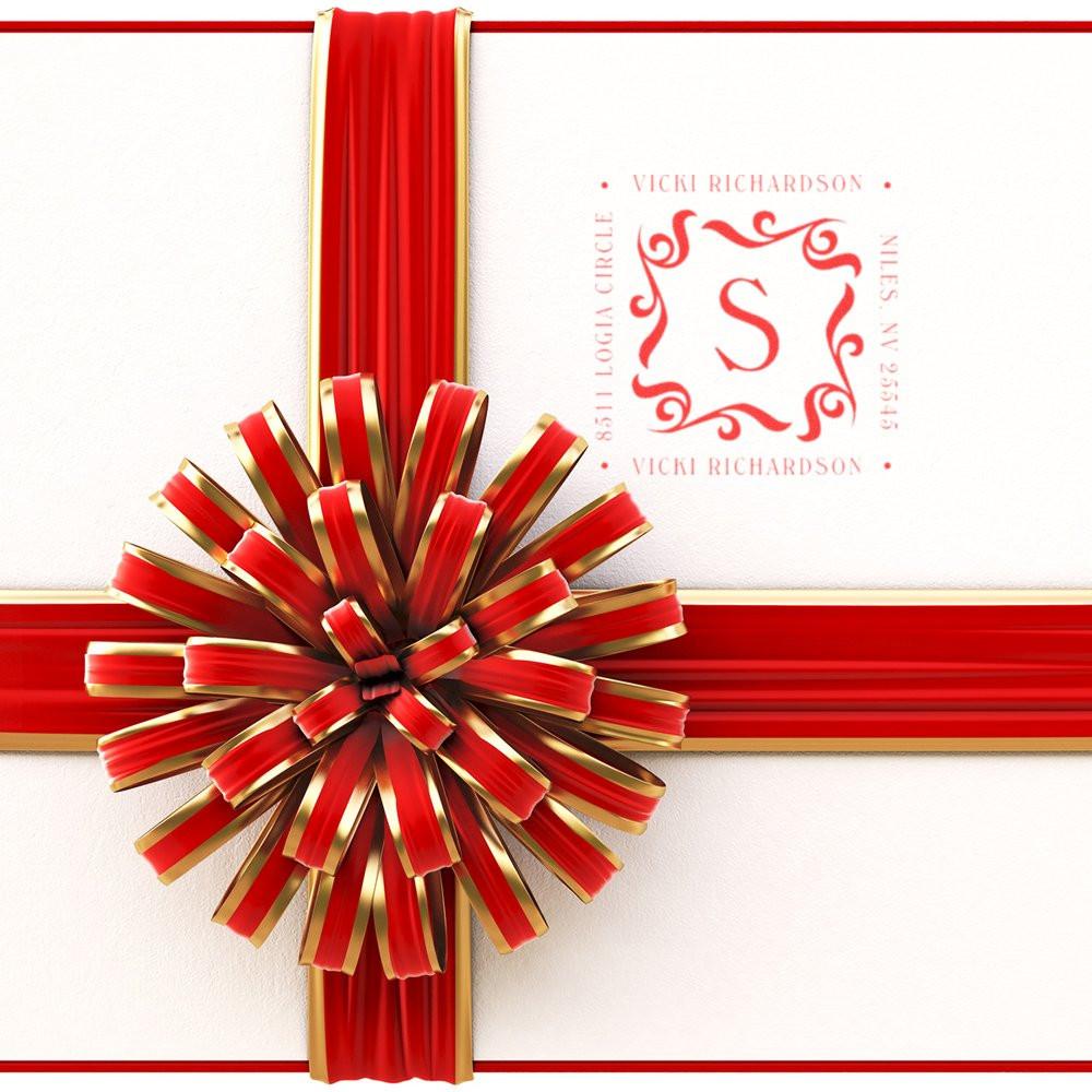 Red and gold ribbon bow tied on a white wedding invitation card with monogram S, ornate crest design, and Vicki Richardson branding.