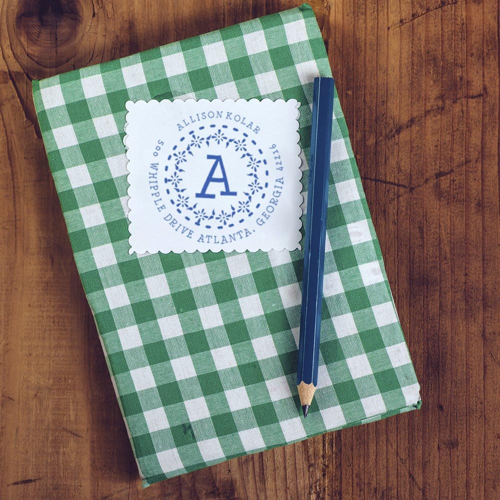 Personalized address rubber stamp on green gingham notebook with pencil, ideal for custom return address and stationery branding.