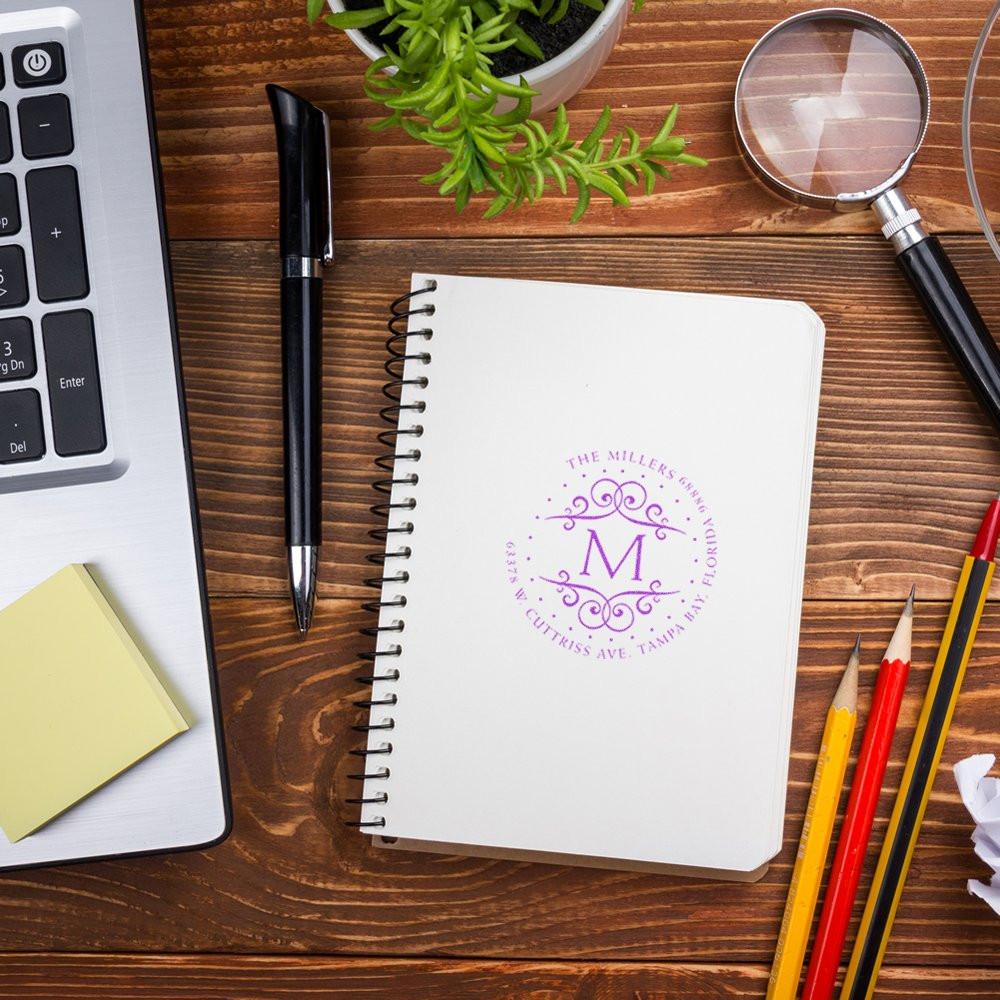 Custom rubber stamp impression on notebook with monogram and address, ideal for personalized stationery and business branding.