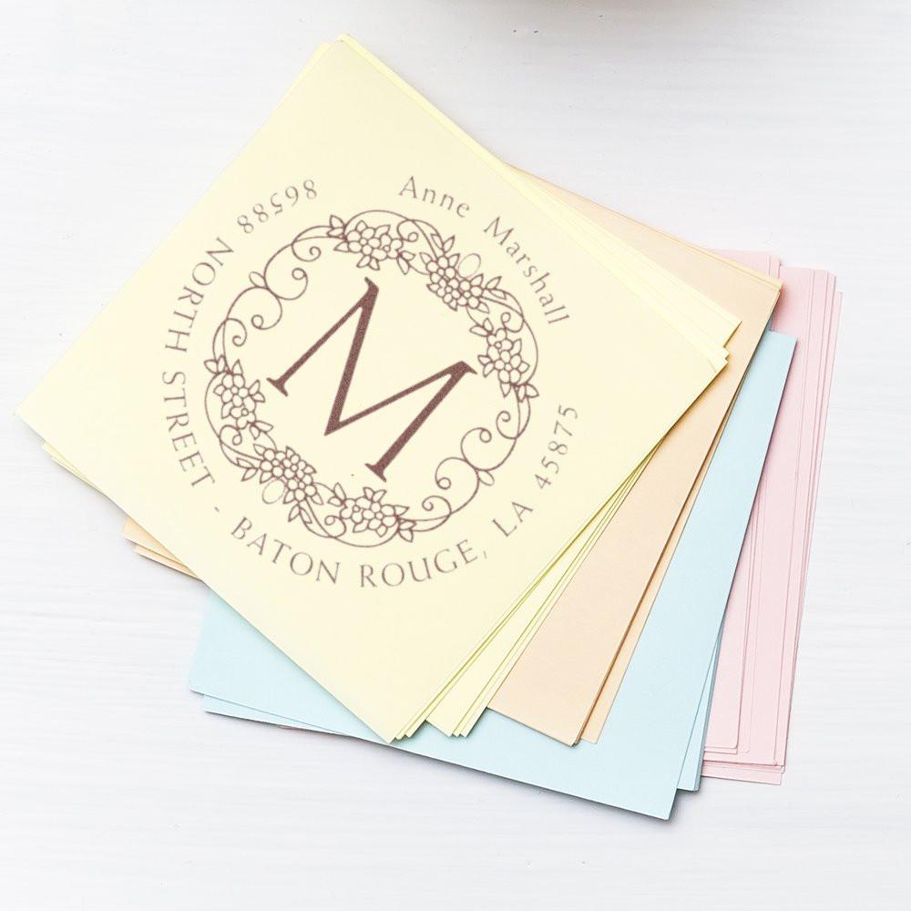 Custom monogram rubber stamp with floral wreath return address design on pastel stationery