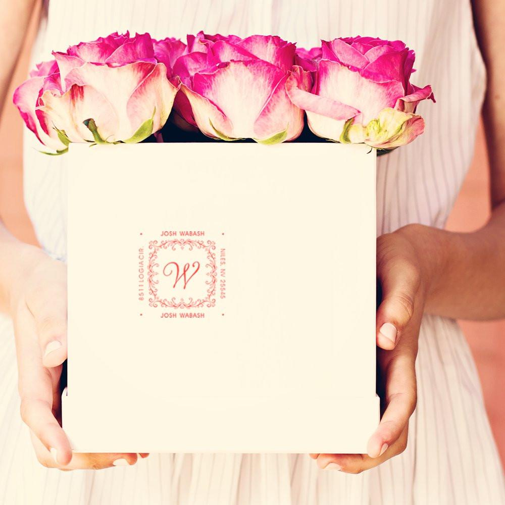 Custom wedding rubber stamp on cream gift box with pink roses, ideal for personalized monogram packaging.