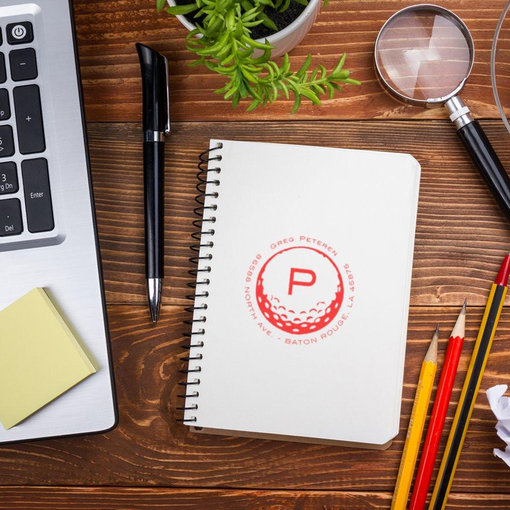 Custom monogram rubber address stamp impression on notebook for personalized mail, stationery, and branding.
