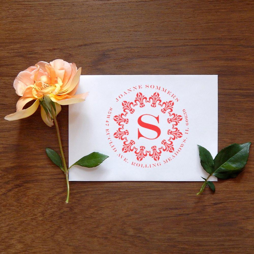 Custom monogram rubber stamp with floral border on paper, ideal for personalized wedding invitations and stationery.