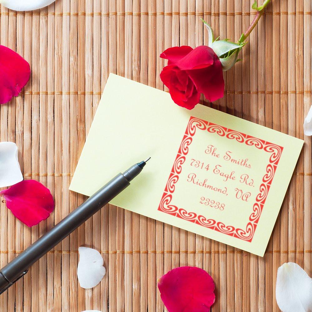 Personalized return address rubber stamp on stationery with pen and rose petals, ideal for wedding invitations and thank-you cards.