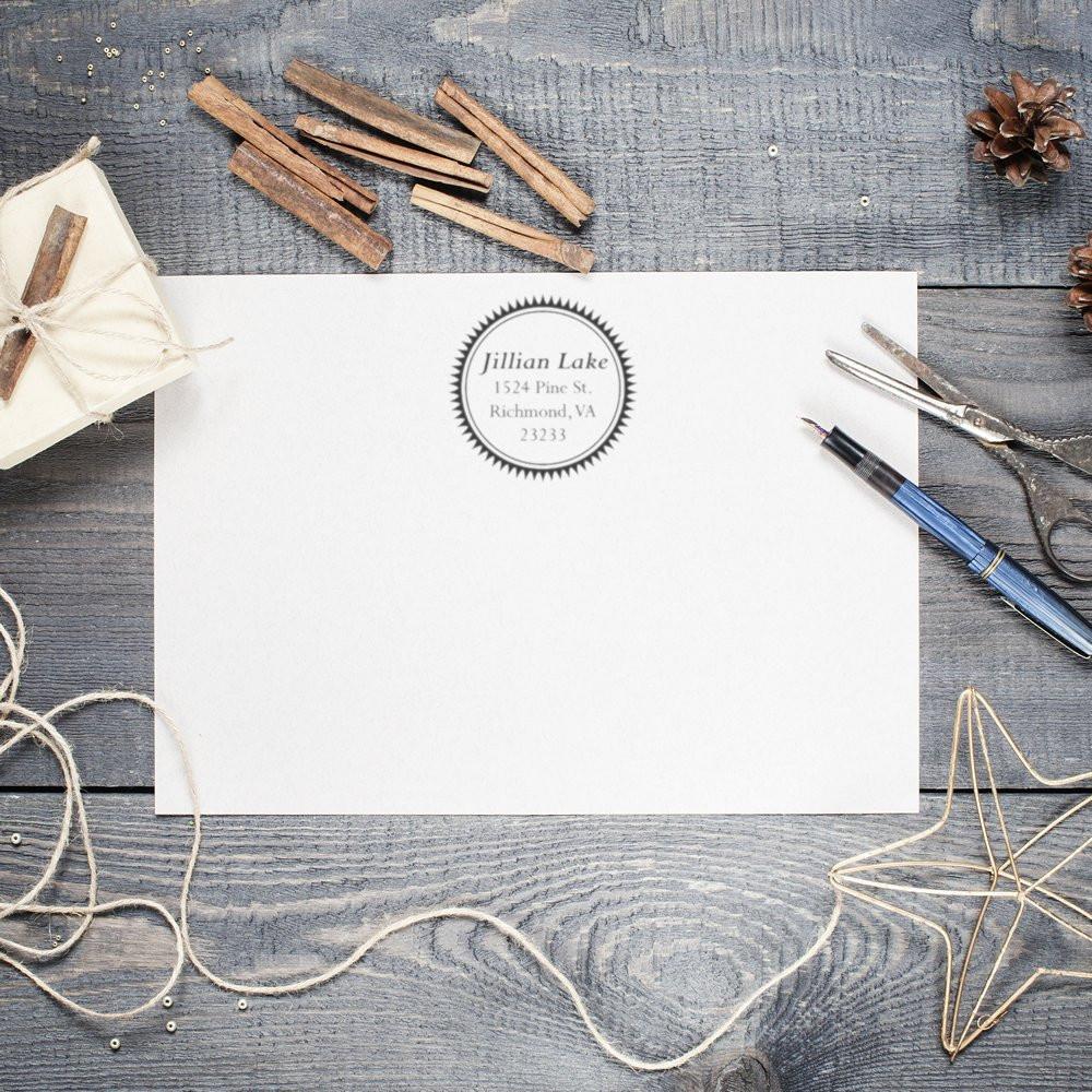 Custom return address rubber stamp on a white envelope, styled with rustic stationery and craft supplies.