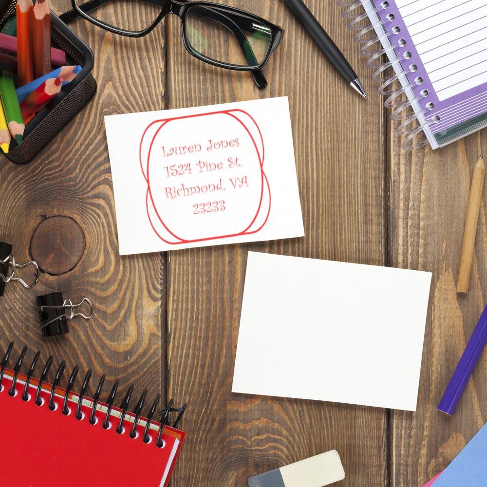 Custom address rubber stamp on paper with office supplies for personalized envelope and mailing use.
