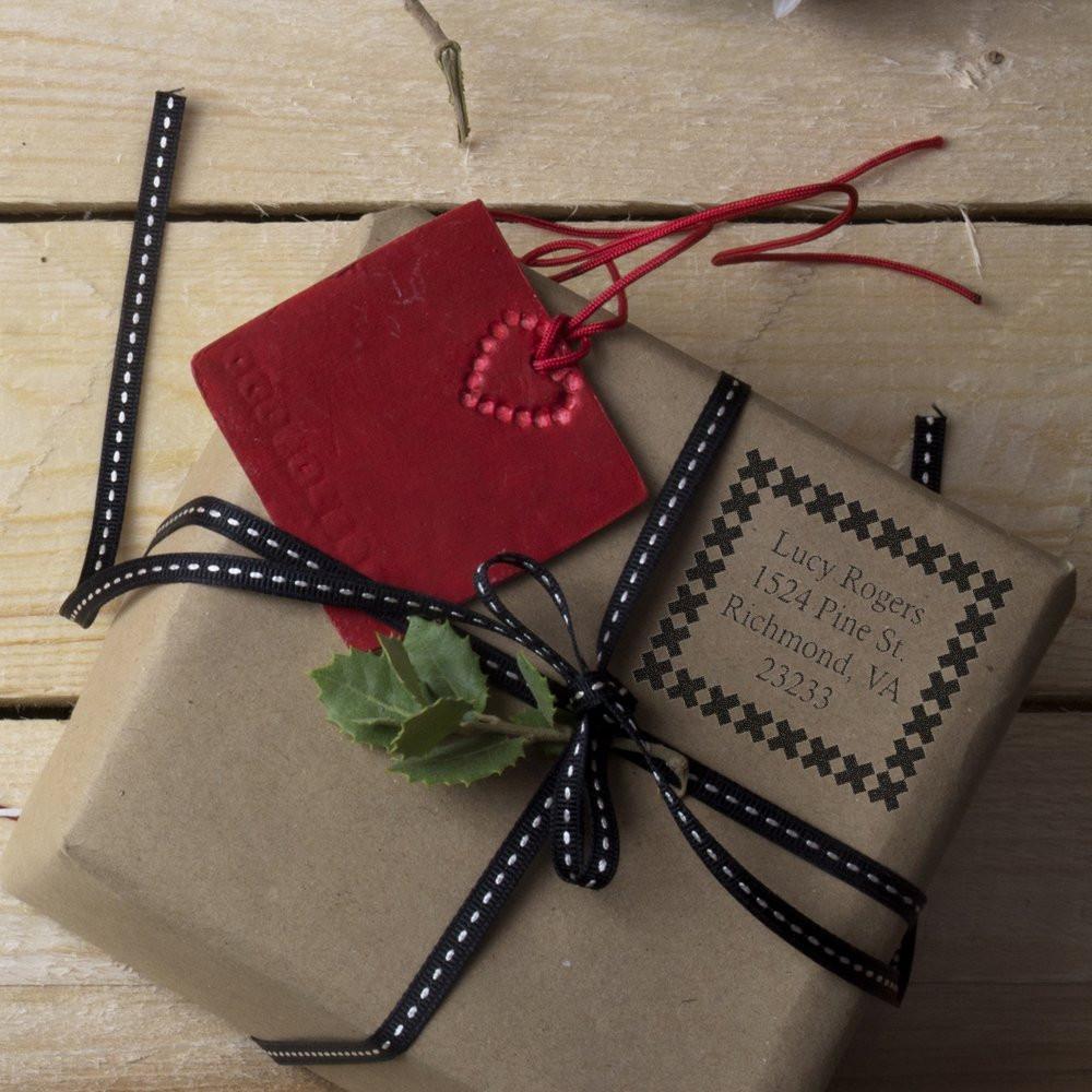 Custom rubber stamp address label on kraft gift wrap, with ribbon and red tag, for personalized packaging and mailing.
