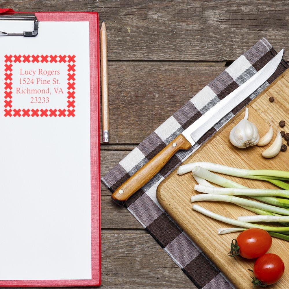 Custom return address rubber stamp on clipboard with red address imprint for personalized mail.