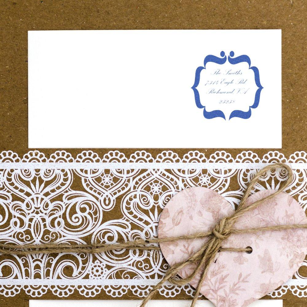 Custom rubber address stamp on a white invitation envelope, styled with lace trim and twine heart for handmade wedding stationery.