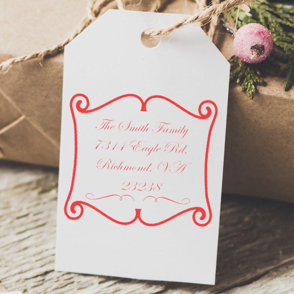 Custom return address rubber stamp on white gift tag for wedding or holiday packaging, featuring decorative red script.