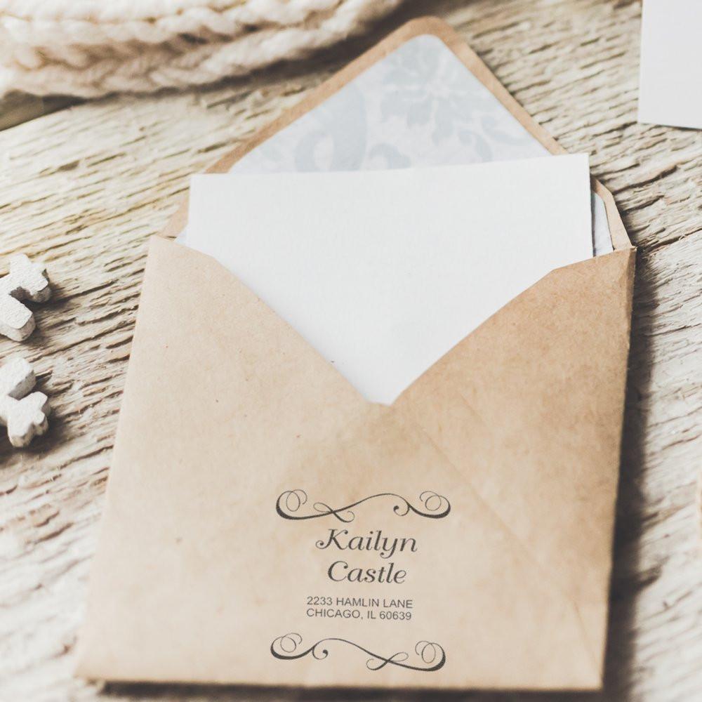 Custom return address rubber stamp on a kraft envelope for wedding invitations and personalized mailing.