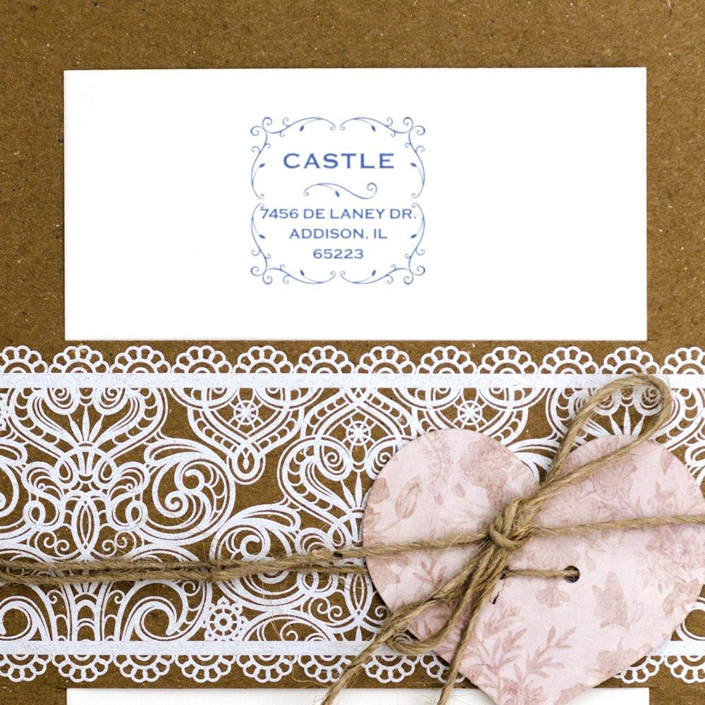 Custom return address rubber stamp on wedding stationery with ornate lace paper and heart gift tag tied with twine