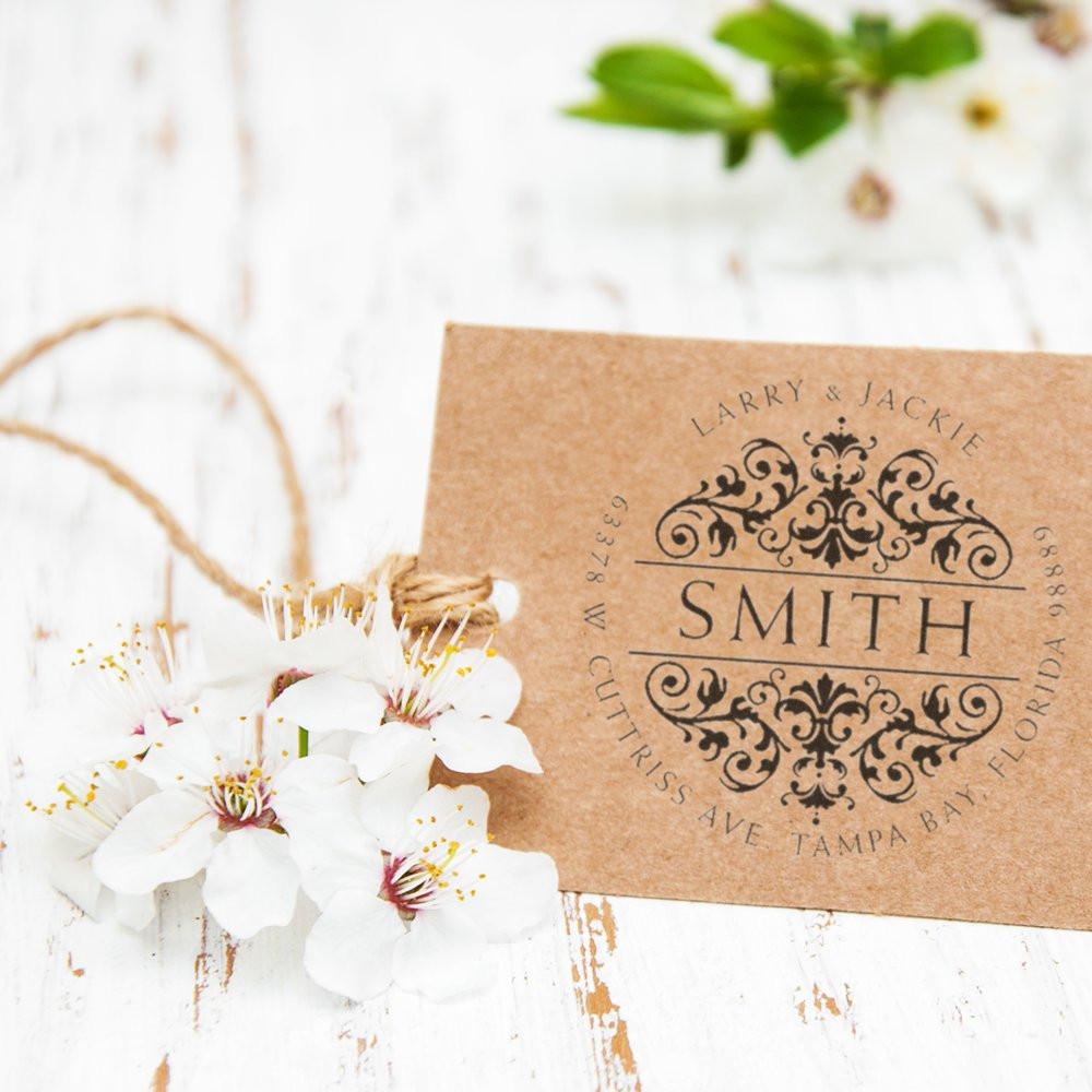 Custom wedding return address rubber stamp with ornate Smith monogram on kraft cardstock, styled with white flowers.