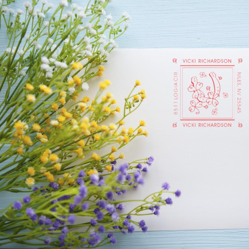 Custom floral return address rubber stamp impression on white stationery, styled for personalized mailings and branding.
