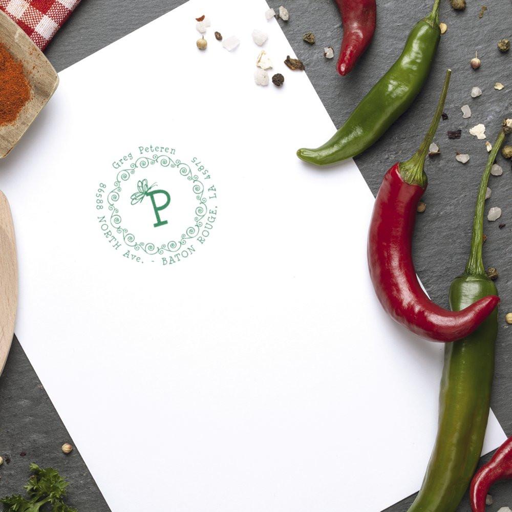 Custom rubber stamp impression on paper with a green monogram seal, styled with chili peppers for restaurant branding.