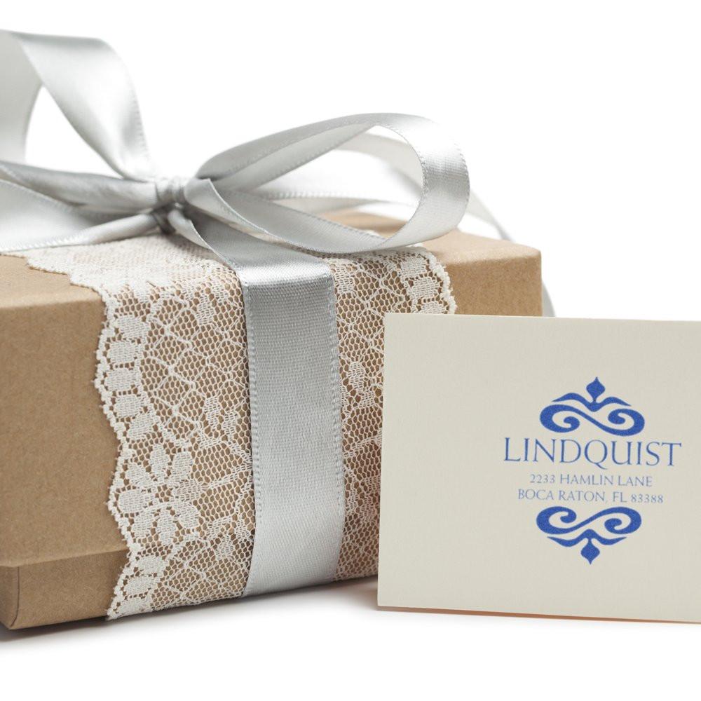 Custom rubber stamp logo on gift packaging, showing branded address card beside a wrapped present with ribbon and lace.