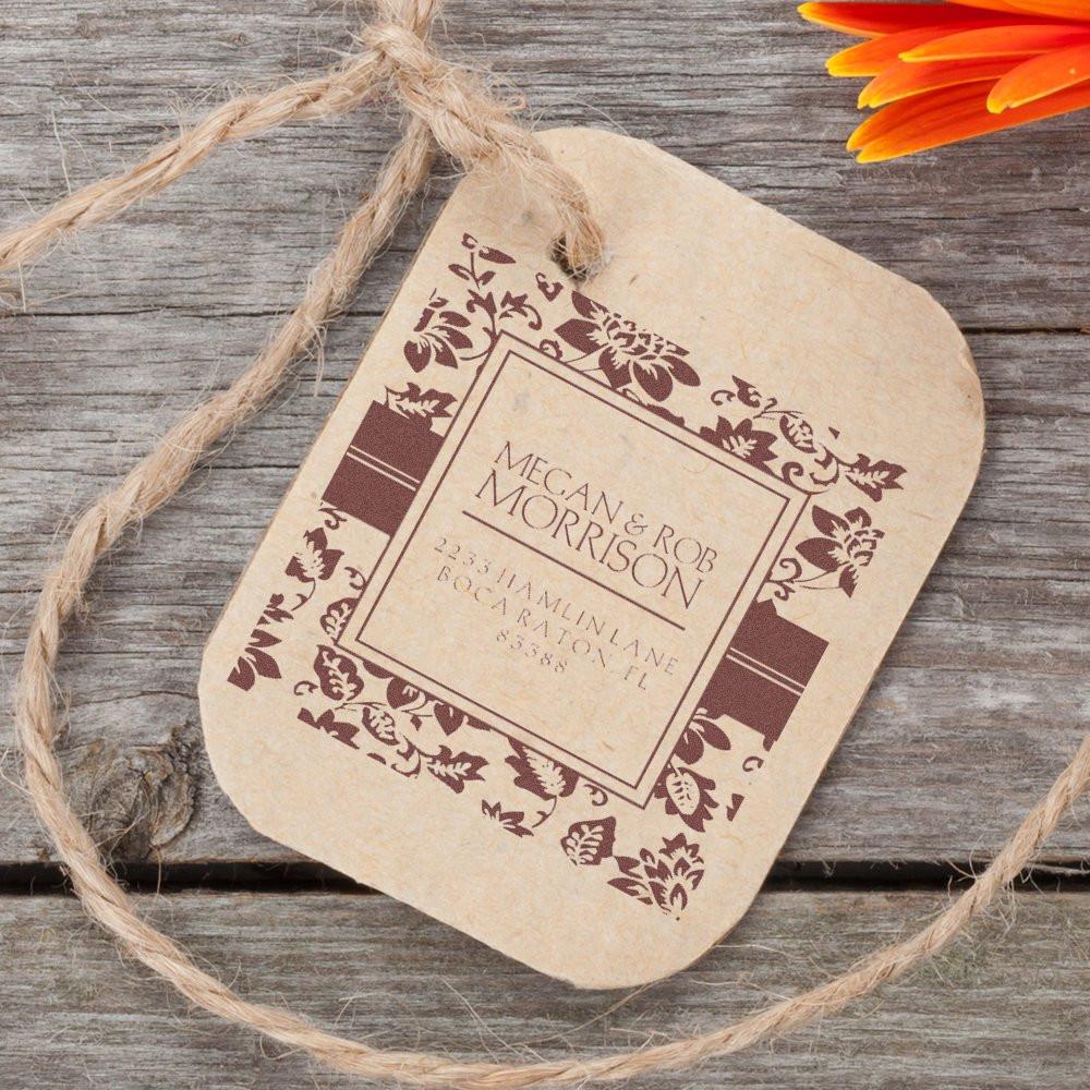 Personalized floral rubber stamp on kraft tag for wedding invitations, featuring monogram names and return address.