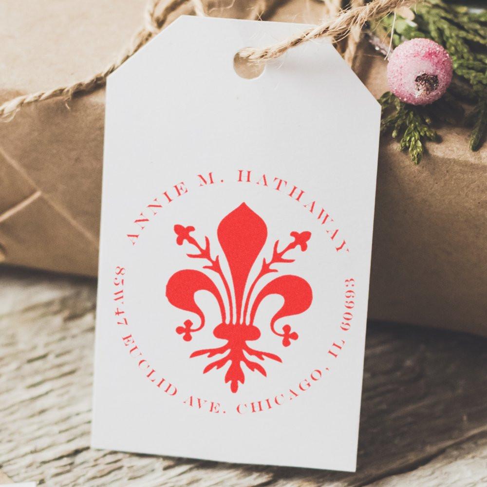 Custom fleur-de-lis return address rubber stamp on a white gift tag for wedding favors or packaging.