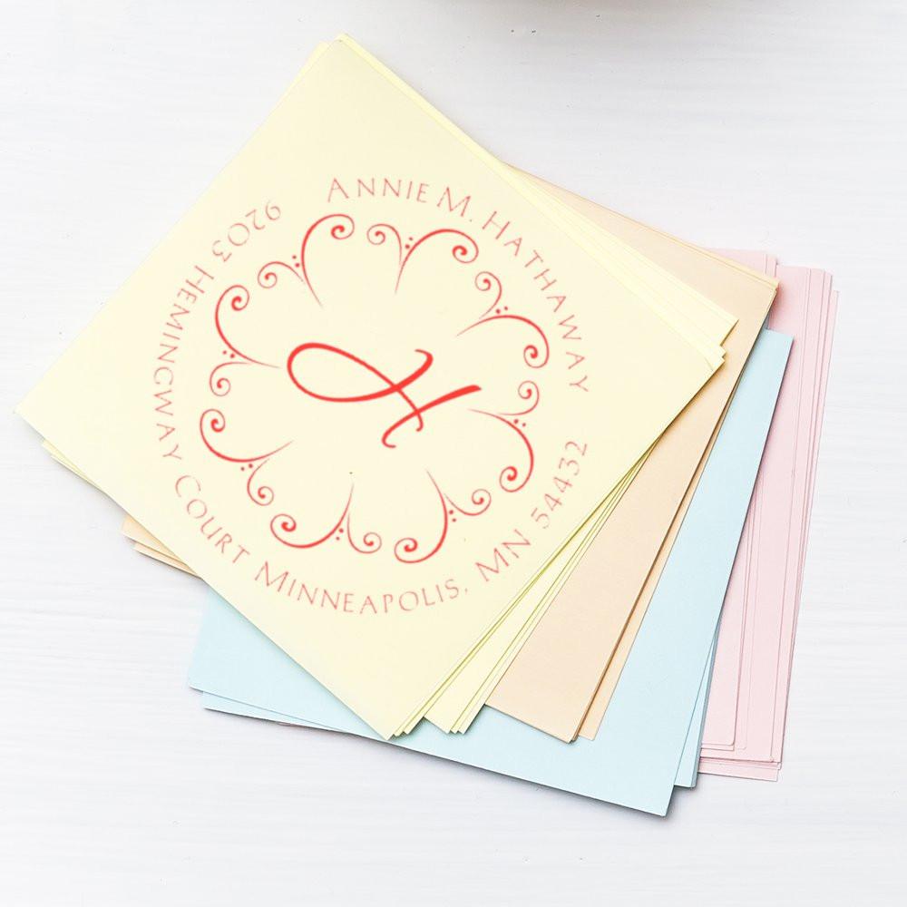 Custom rubber stamp with monogram and address on pastel stationery for personalized wedding invitations or business mail.