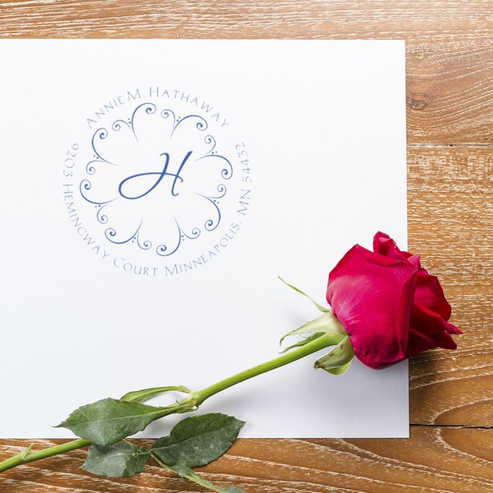 Personalized wedding address rubber stamp with floral monogram H on stationery beside a red rose.