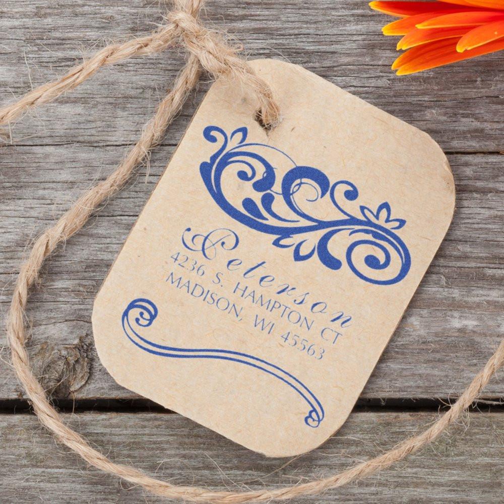Personalized rustic wedding gift tag with blue floral monogram and address on kraft paper, tied with twine.