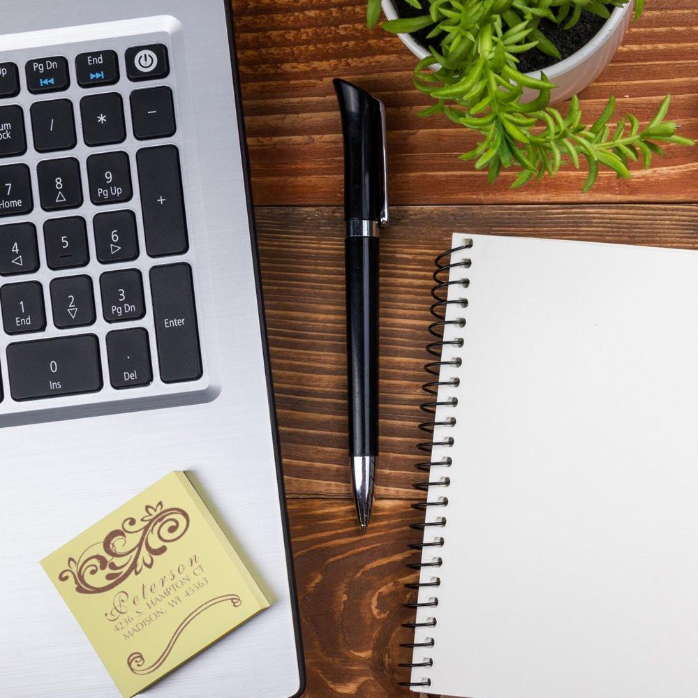 Custom rubber stamp design sample on desk with laptop, pen and notebook for personalized business branding.