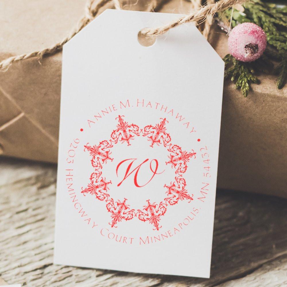Custom monogram rubber stamp on a gift tag with floral wreath design and return address for wedding or holiday packaging.