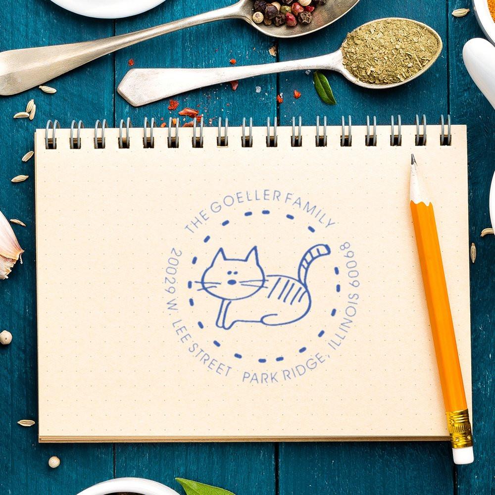 Custom rubber address stamp with cat family design and address imprint on notebook, showcasing personalized stamp artwork.