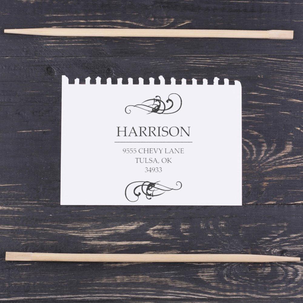 Custom address rubber stamp proof with decorative flourishes and family name on paper, shown with wooden stamping tools.