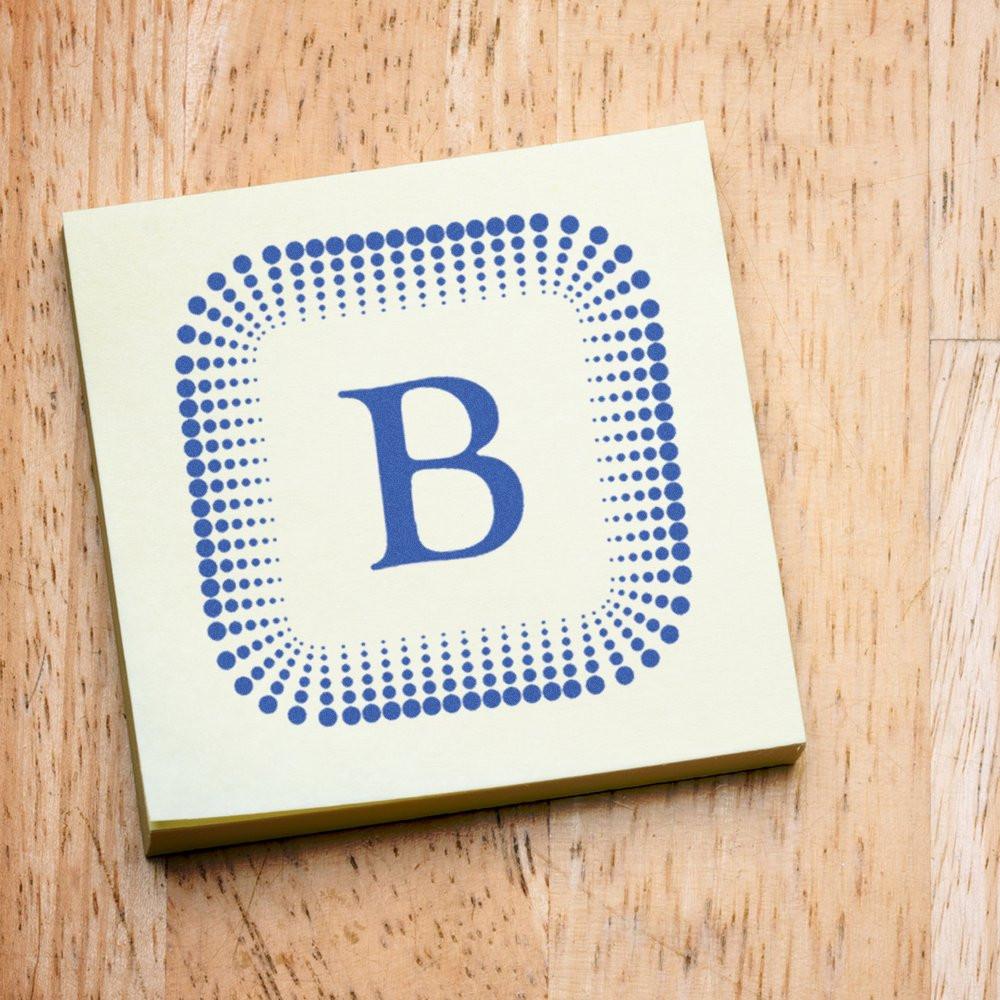 Custom B monogram rubber stamp with blue dot border on a wood background