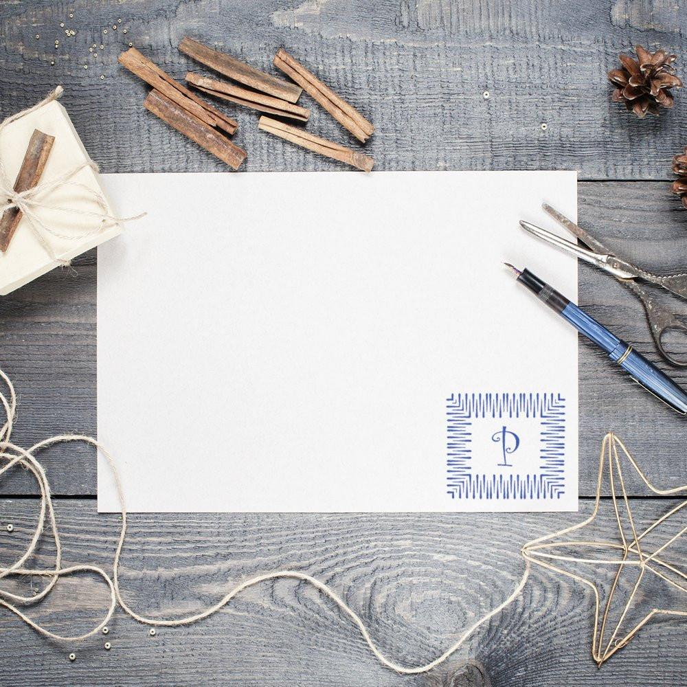 Blank greeting card stationery mockup with blue P monogram, fountain pen, twine, and pinecone on rustic wooden background.