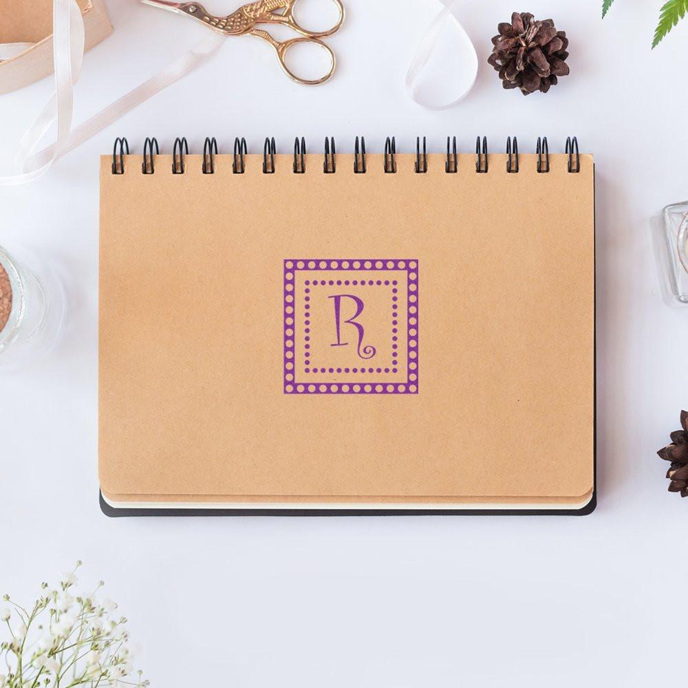 Custom letter R rubber stamp on kraft notebook for personalized stationery, branding, and packaging.
