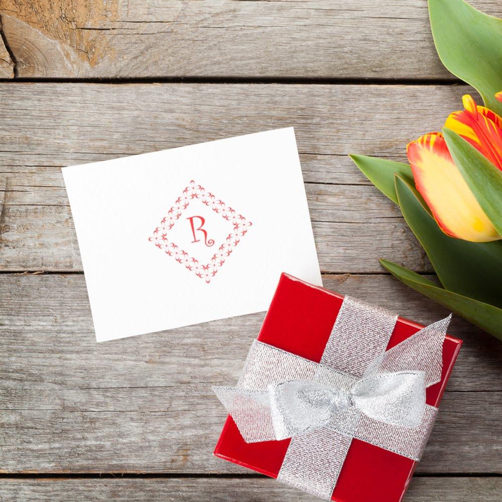 Custom monogram rubber stamp on a gift card beside a wrapped present and tulips, perfect for wedding invitations and packaging.