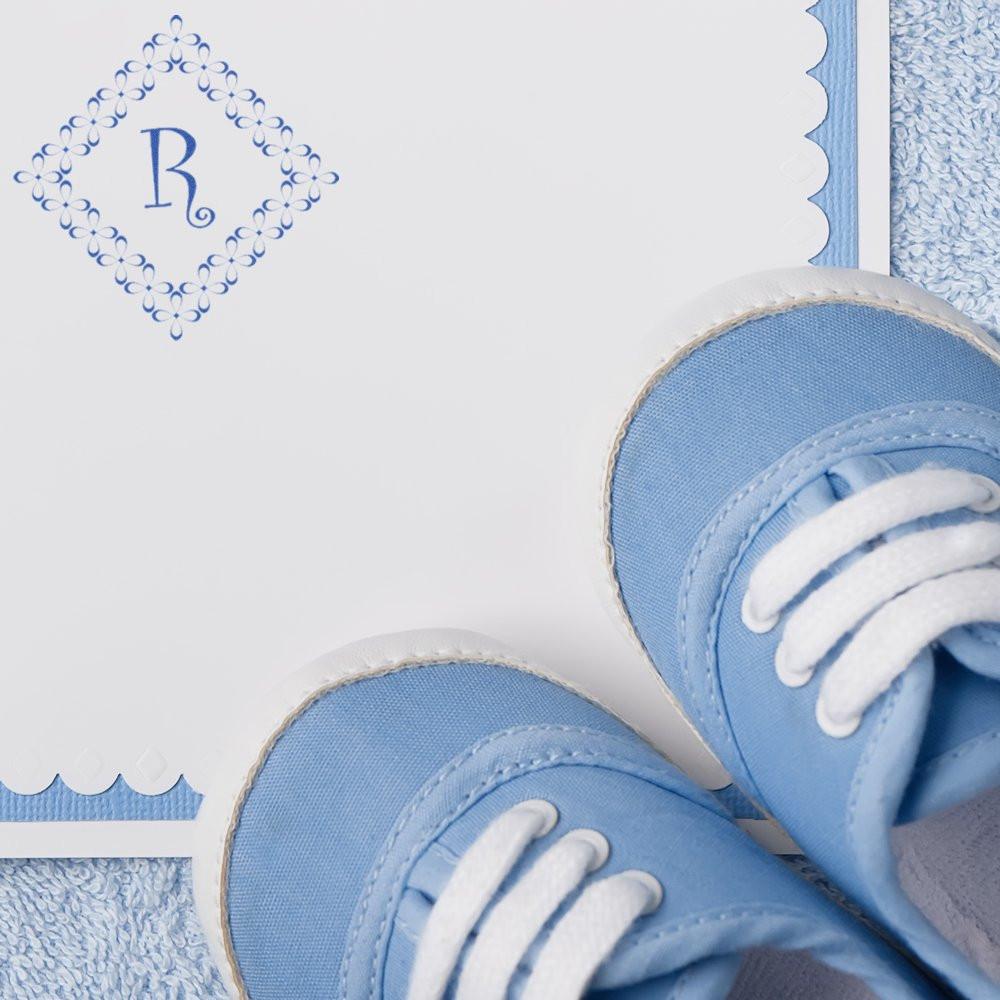 Custom monogram rubber stamp for baby shower stationery, styled with blue baby shoes and a delicate lace border.