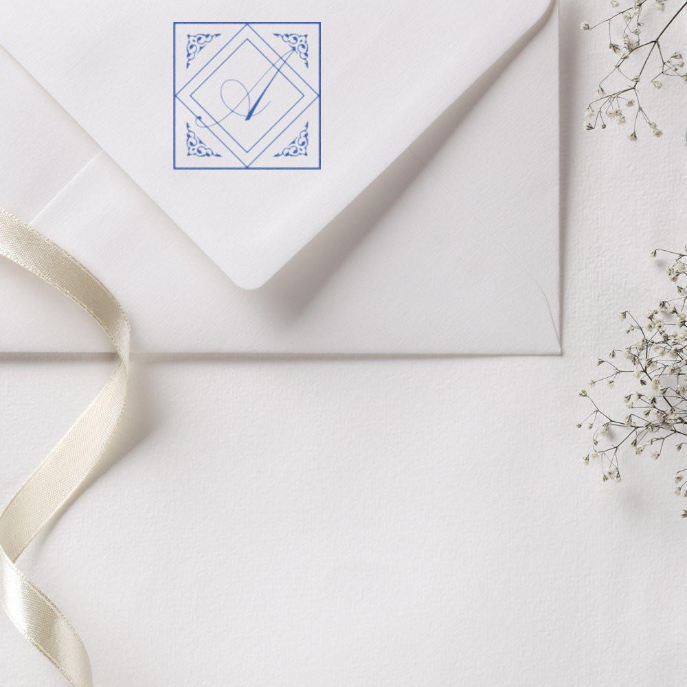Custom blue monogram rubber stamp on a white envelope for elegant wedding invitations and personalized stationery.