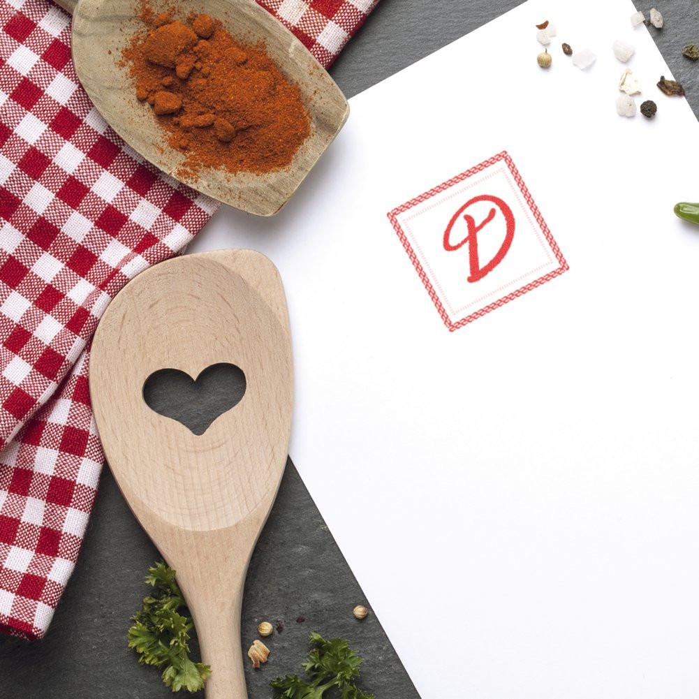 Custom rubber stamp red D monogram on kitchen-themed paper mockup for food branding, packaging, and recipe cards.