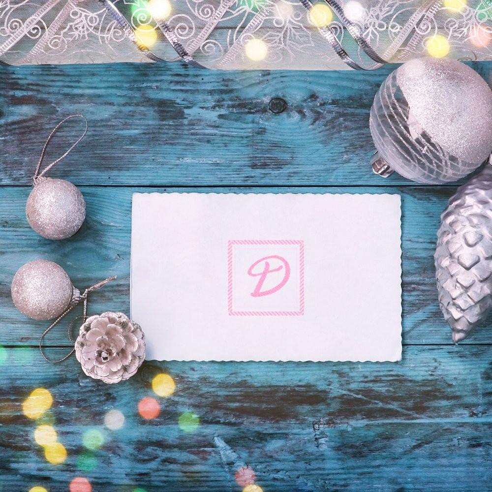 Pink monogram D custom rubber stamp on blank card with silver ornaments, ideal for holiday card making.