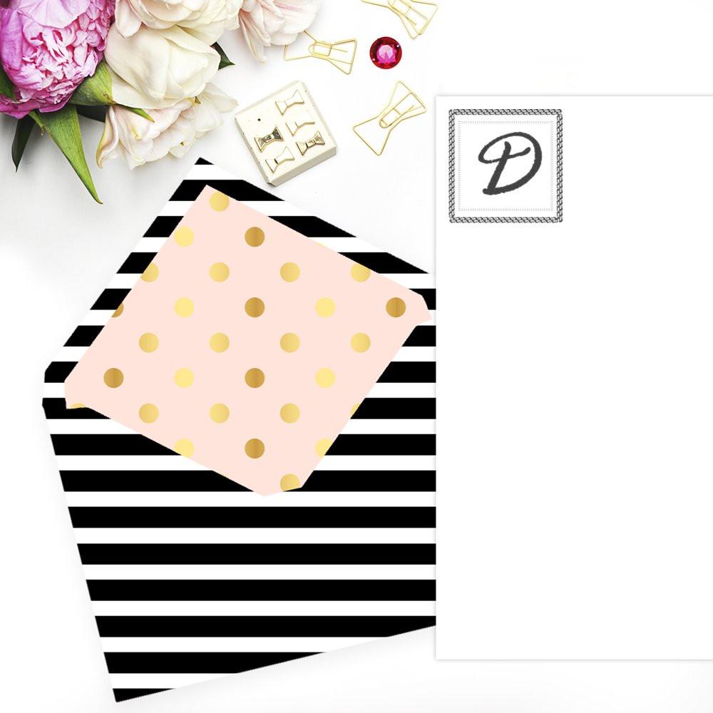 Custom monogram rubber stamp mockup on stationery with striped envelope, pink polka dot insert, and floral accents.