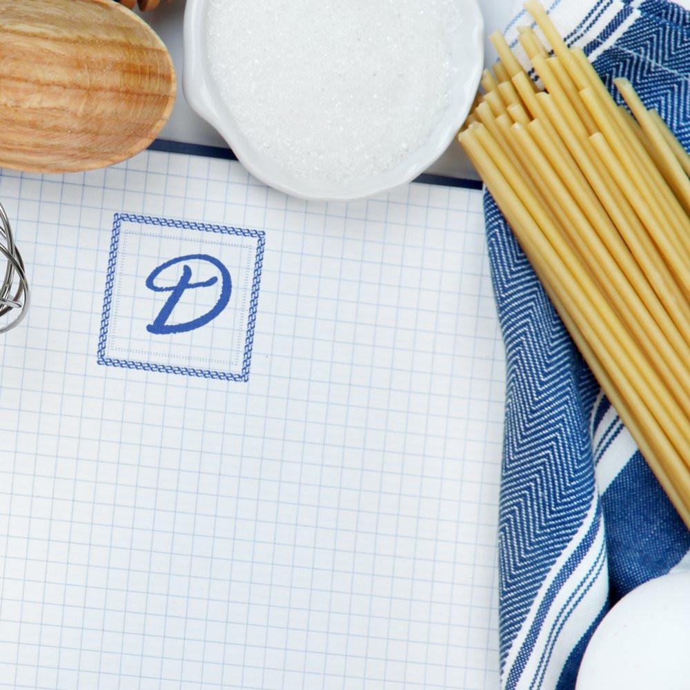 Custom monogram rubber stamp with blue letter D on graph paper, ideal for personalized stationery and branding.