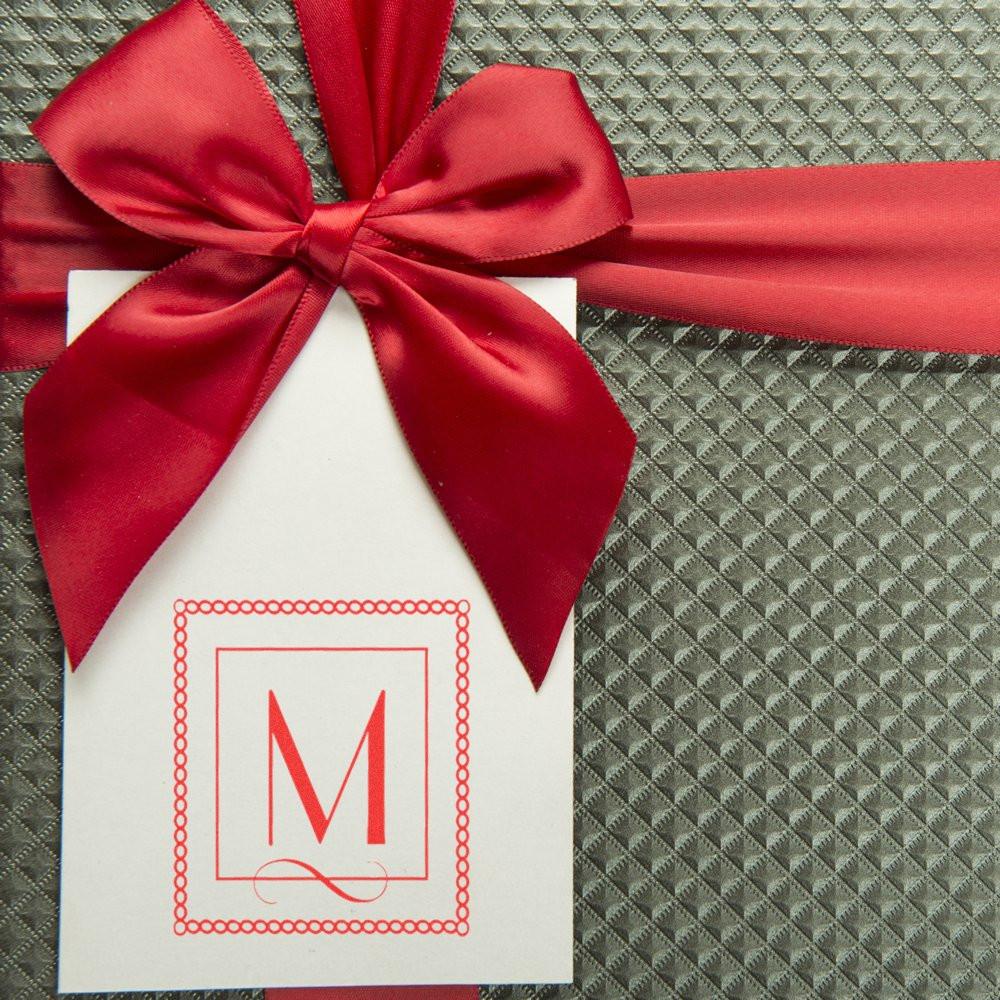Custom monogram rubber stamp on gift tag with red ribbon, perfect for personalized gift packaging and wedding favors.