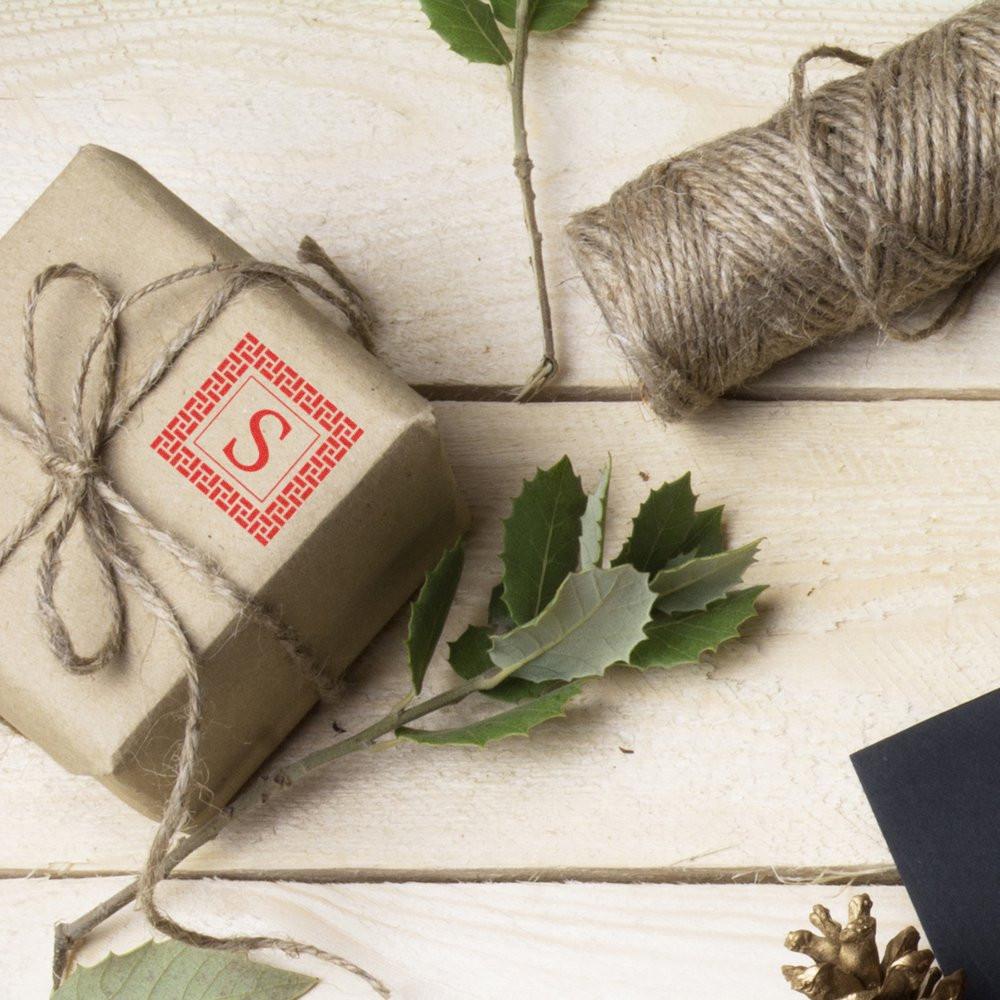 Custom monogram rubber stamp on kraft gift wrap with twine, ideal for personalized packaging and branding.