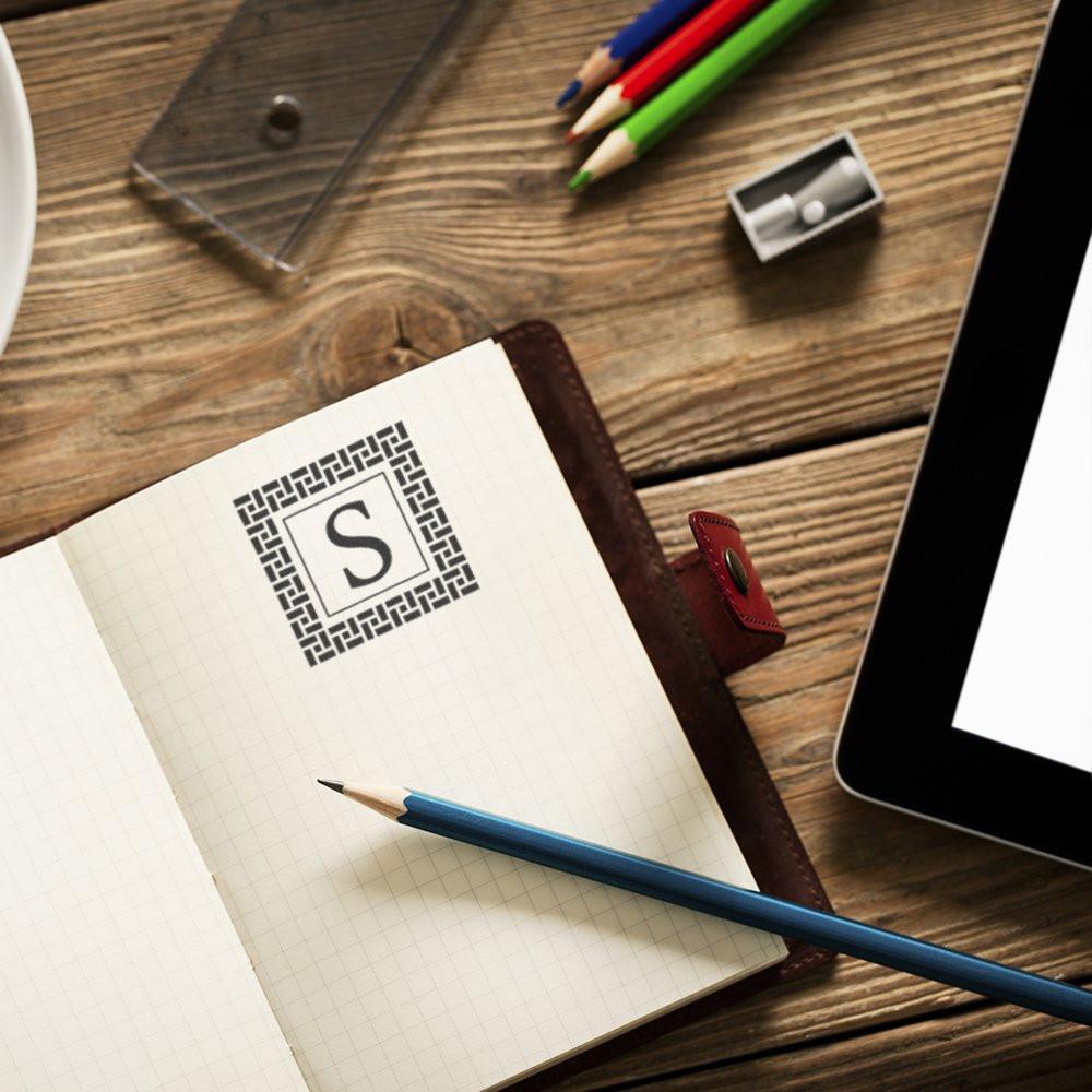 Custom monogram rubber stamp with letter S on notebook for personalized stationery, branding, and paper goods.