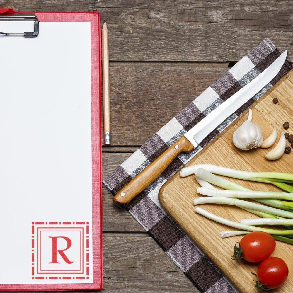 Personalized rubber stamp with red letter R on clipboard, styled with rustic kitchen prep props