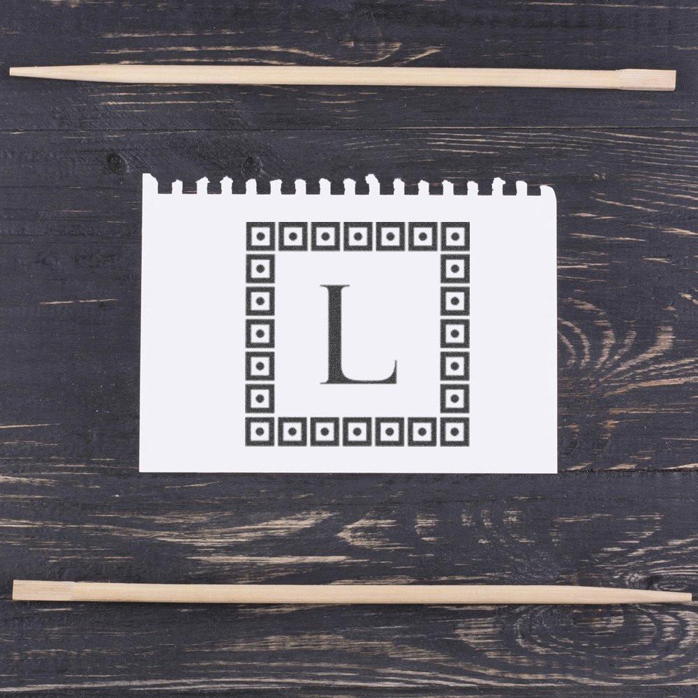 Custom monogram rubber stamp with letter L and decorative border for personalized stationery and branding.