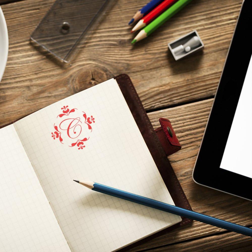 Custom decorative rubber stamp monogram on notebook page, ideal for personalized stationery and branding